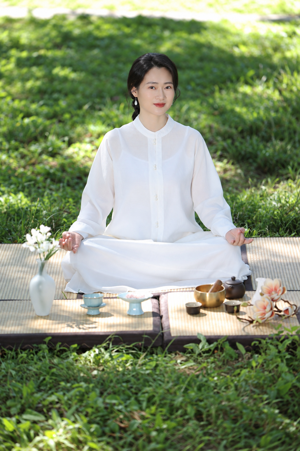 Mei sitting in meditation on a tatami mat outdoors